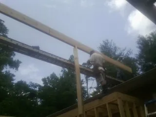 Carpenter setting a ridge beam over a new addition frame — Ice Dam Removal by Roofing Brothers in Evensville