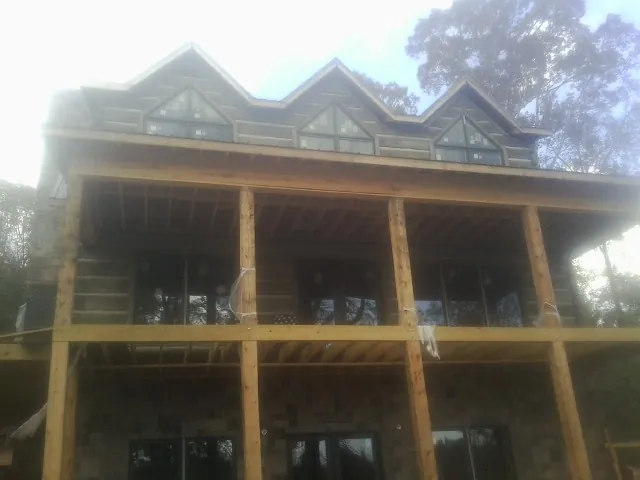 Dormers and porch framing on a large log home under construction — Roof Coating work by our crew in Evensville