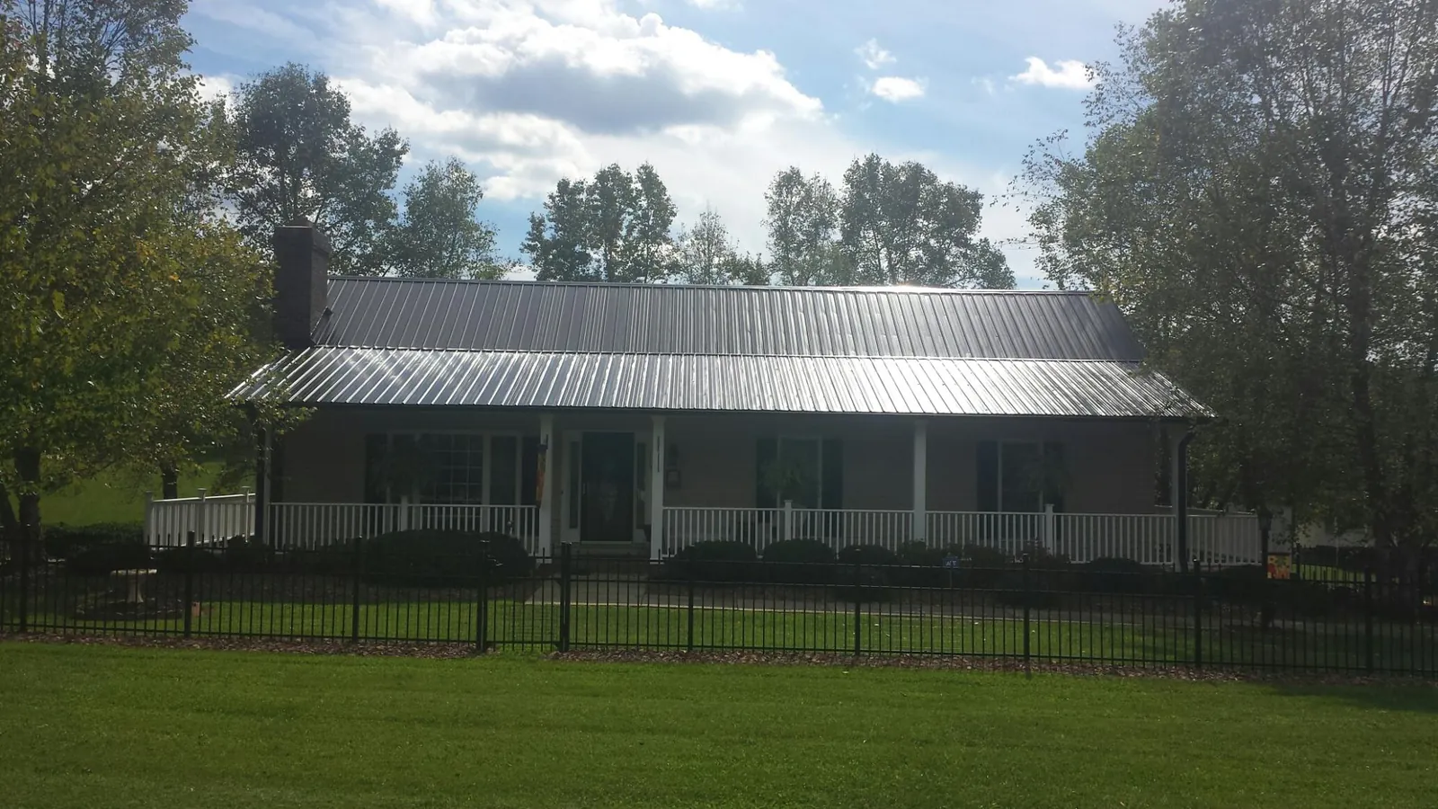 Gray metal roof on a brick ranch with a full width front porch — Gutter Guard Installation work by our crew in Evensville