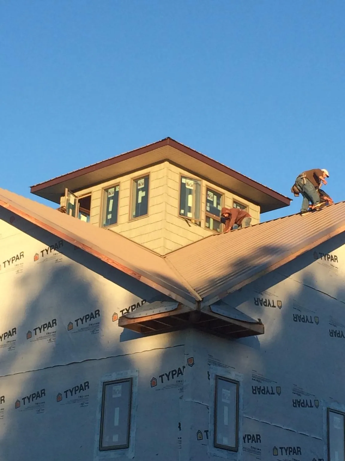 Roofers working around a rooftop cupola on a new metal roof at sunset — Roof Waterproofing in Evensville by Roofing Brothers